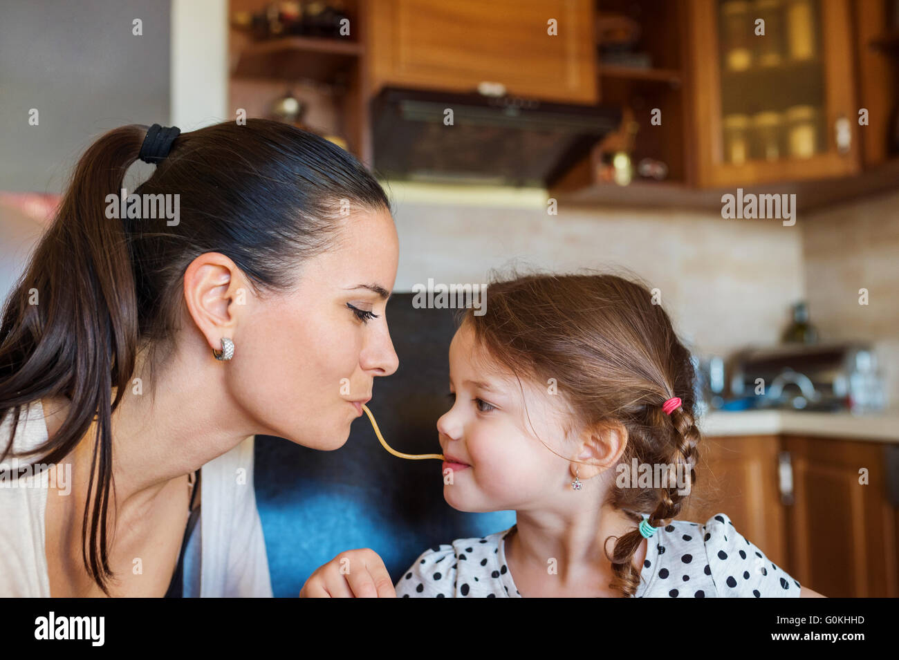 Mother and daughter in the kitchen, eating spaghetti together Stock Photo