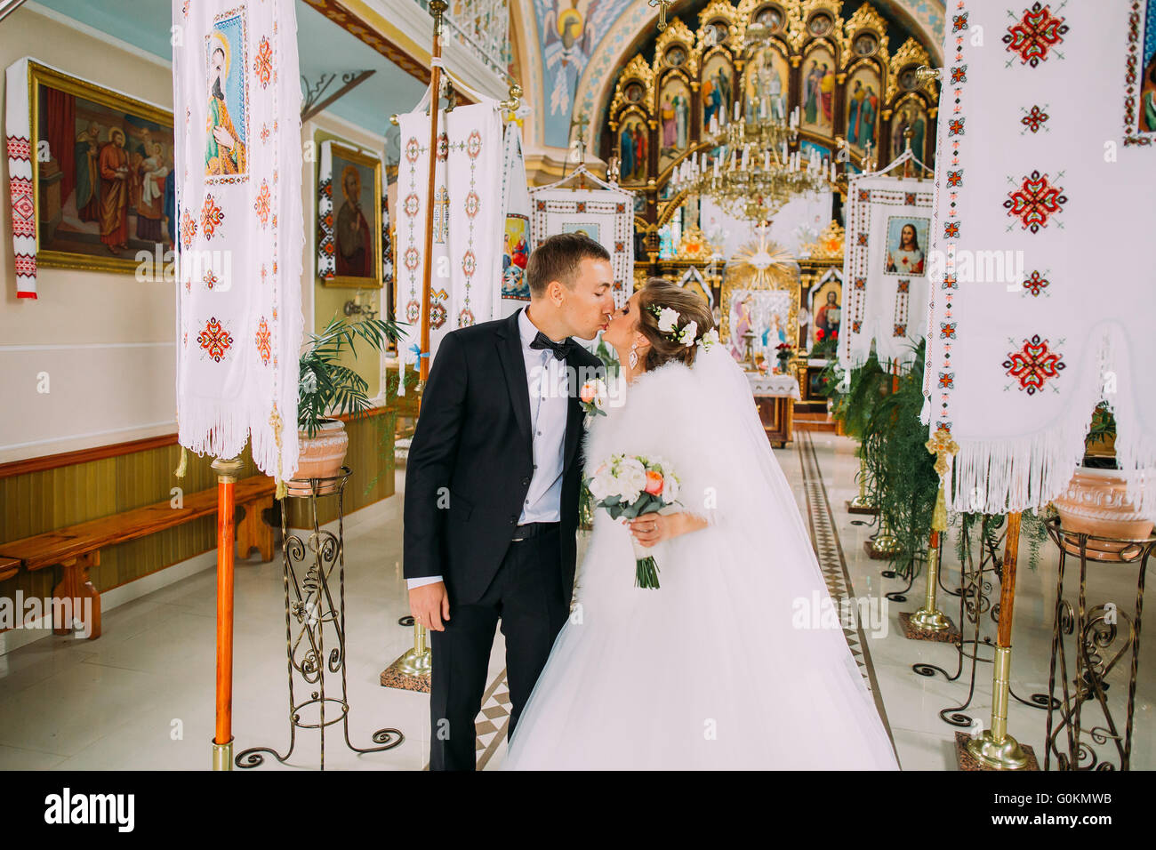 Just married bride and groom walking out of church kissing Stock Photo