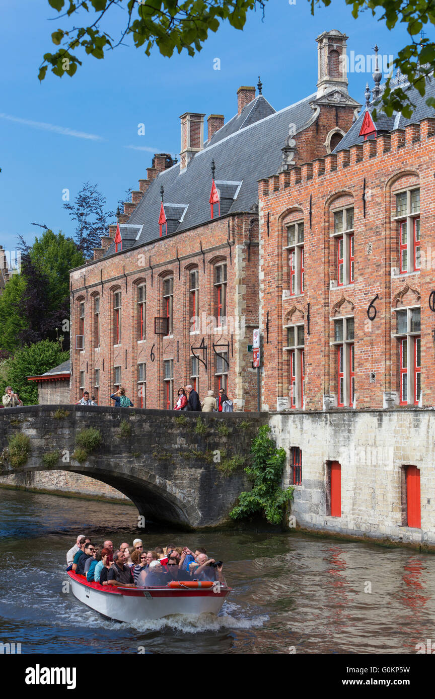 Boat full of tourists pass under the Blinde-Ezel Bridge in Huidenvettersplein, Bruges, Belgium. Stock Photo