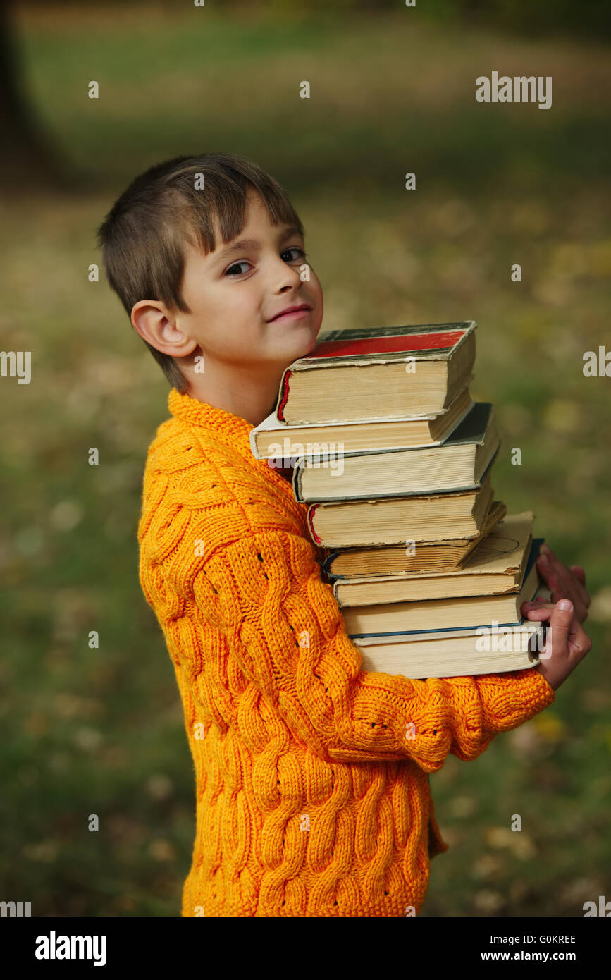 little happy boy carrying stack of books Stock Photo