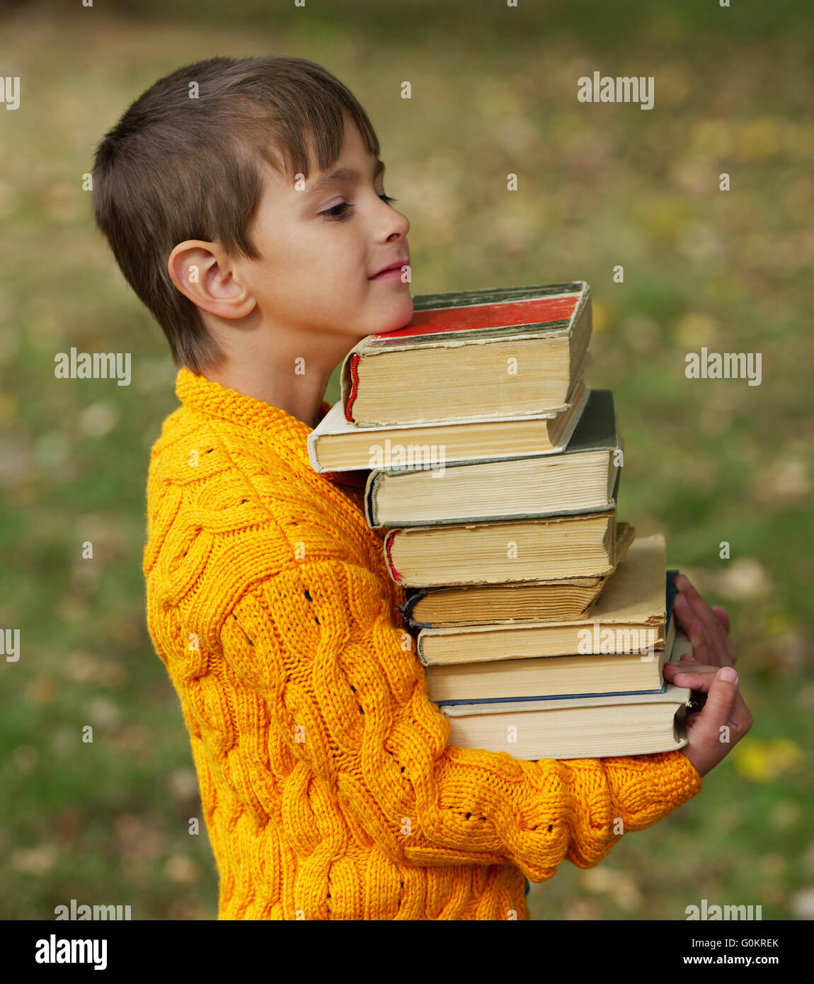 little happy boy carrying stack of books Stock Photo