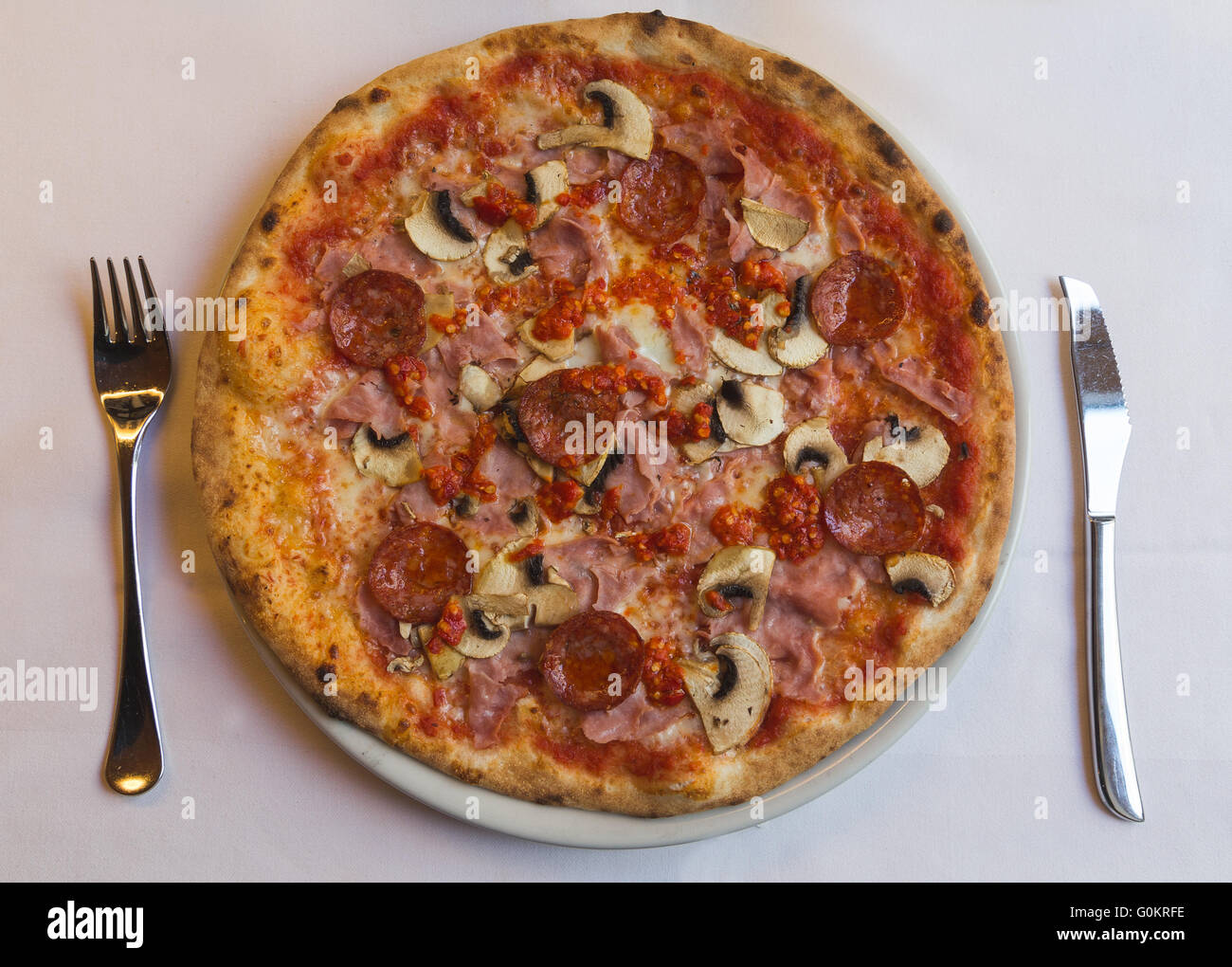 High angle of a Salami, Ham, Mushroom, Chilli and Tomatoe Italian Pizza Stock Photo