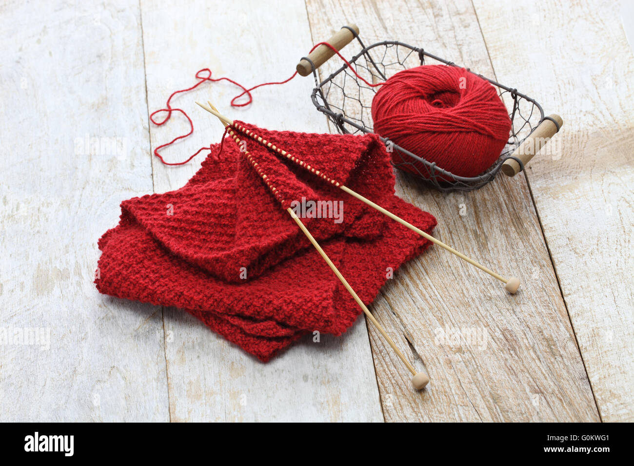 hand knitted red scarf, yarn ball and knitting needles, handmade christmas present Stock Photo