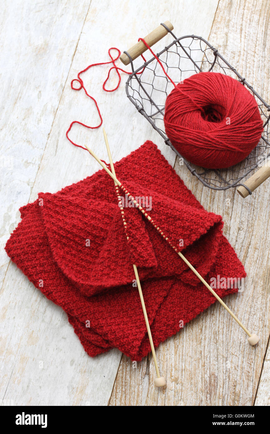 hand knitted red scarf, yarn ball and knitting needles, handmade christmas present Stock Photo