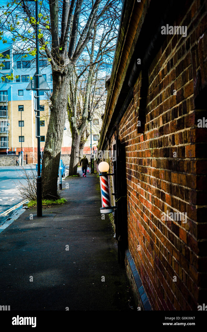 A barber's pole outside a hairdressers in an undercroft below a bridge parapet Stock Photo