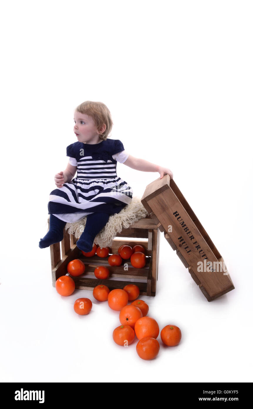 young girl playing on fruit market orange boxes, Stock Photo