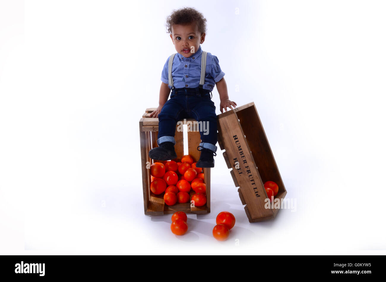 young jamaican boy sitting on fruit boxes full of oranges,SS Empire Windrush generation 1948 Stock Photo