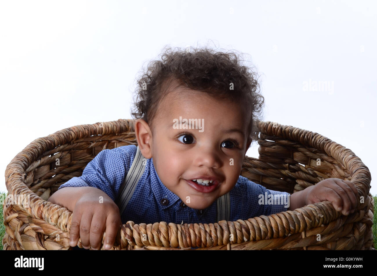 young mixed race, ethnic boy playing and exploring in a wicker basket Stock Photo