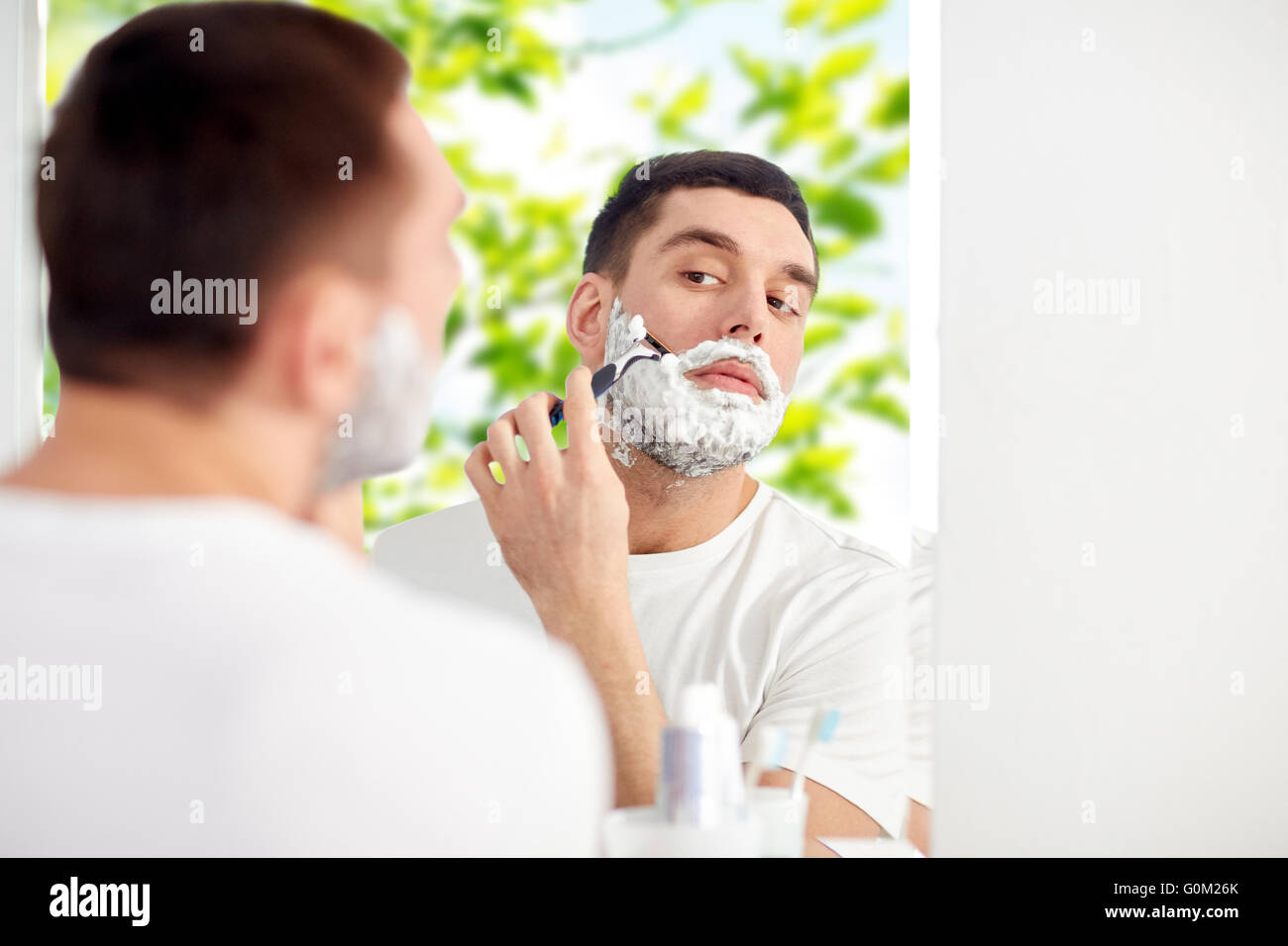 man shaving beard with razor blade at bathroom Stock Photo