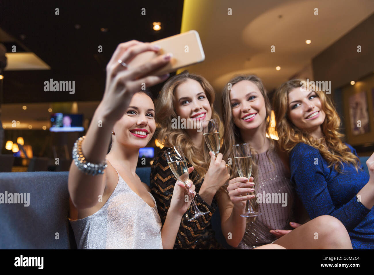 party, technology, nightlife and people concept - smiling friends with  smartphone taking selfie in club. Stock Photo