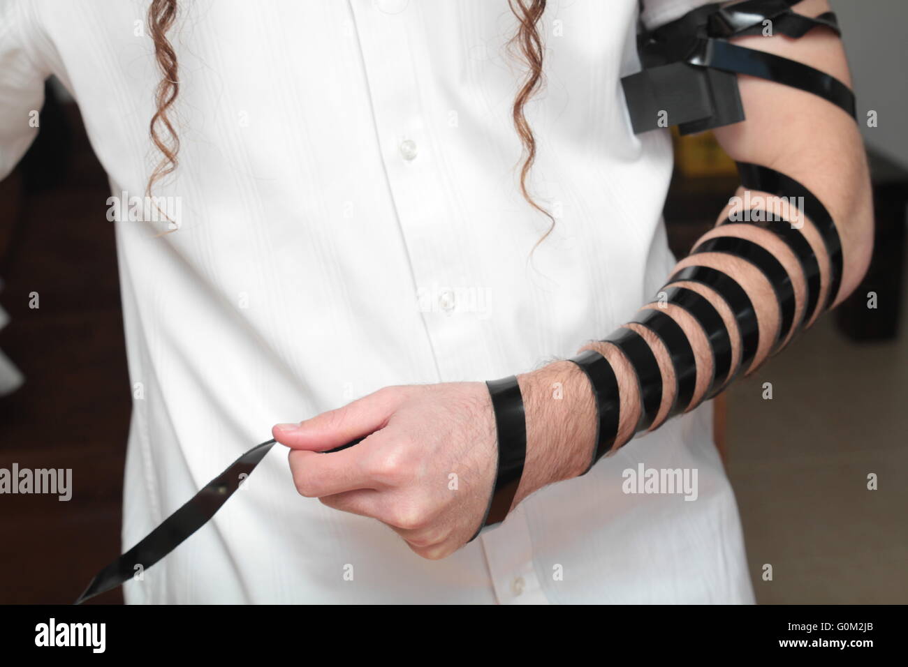 Jewish Man wrapped in tefillin pray . A religious orthodox Jew with arm