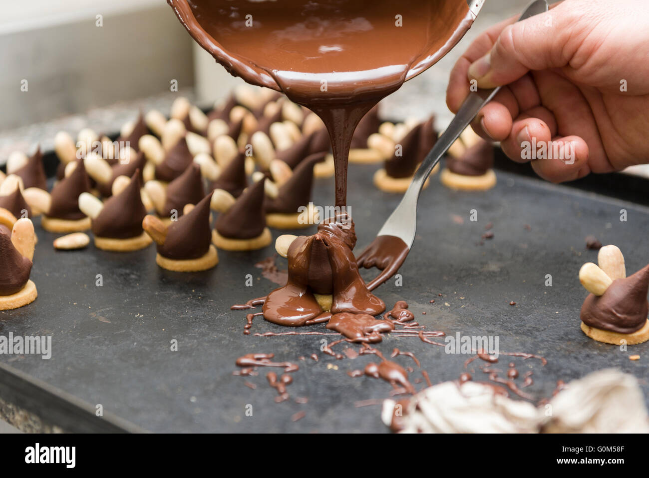 pastry chef covering the biscuits with melted chocolate Stock Photo