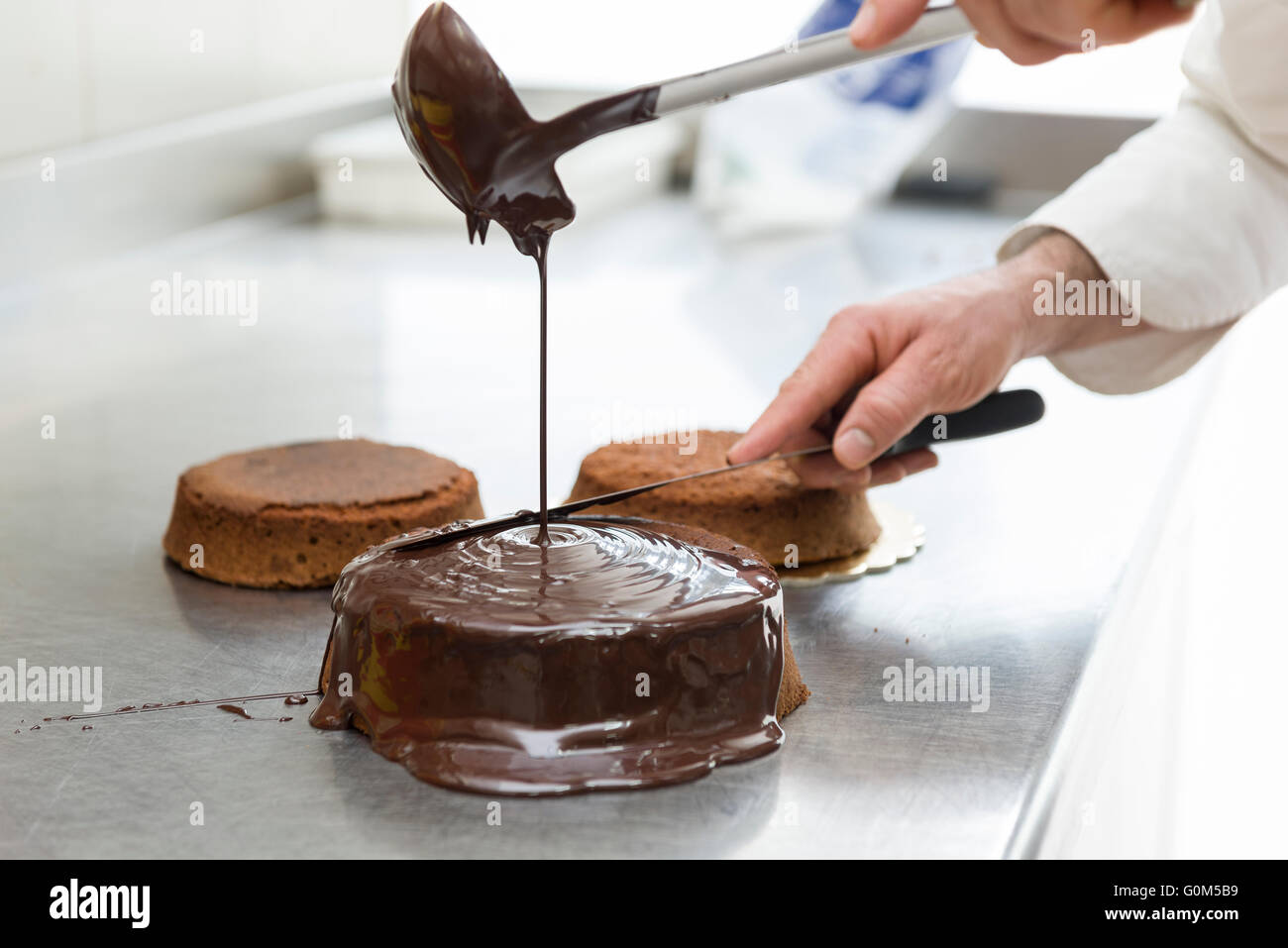 pastry chef covering cake with melted chocolate Stock Photo