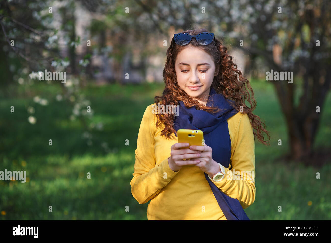 technology and people concept - smiling young woman texting on smartphone Stock Photo