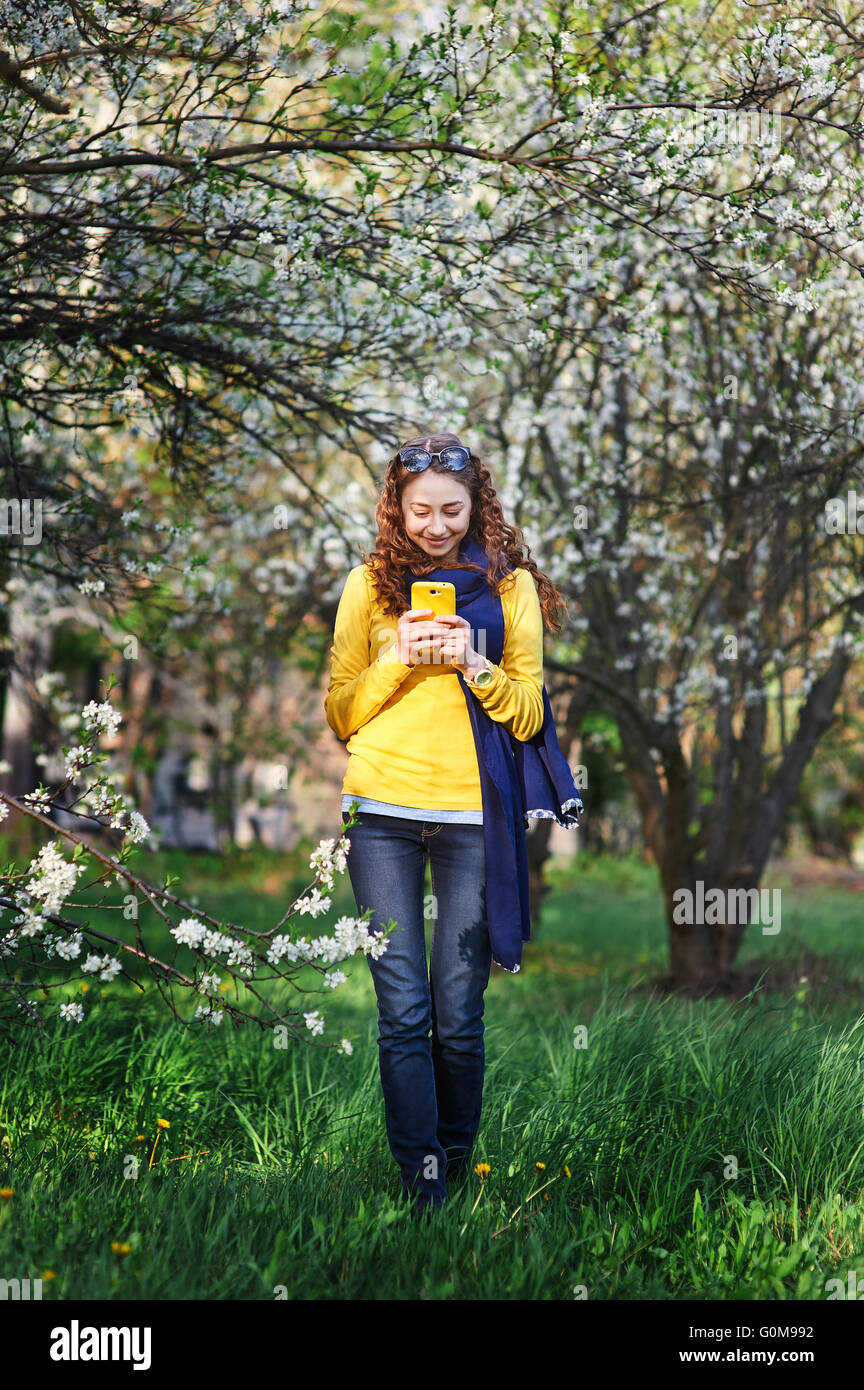 technology and people concept - smiling young woman texting on smartphone Stock Photo