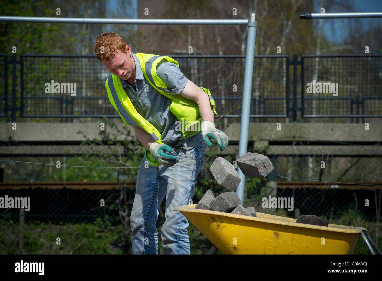 Young man throwing bricks in a wheelbarrow Stock Photo Alamy
