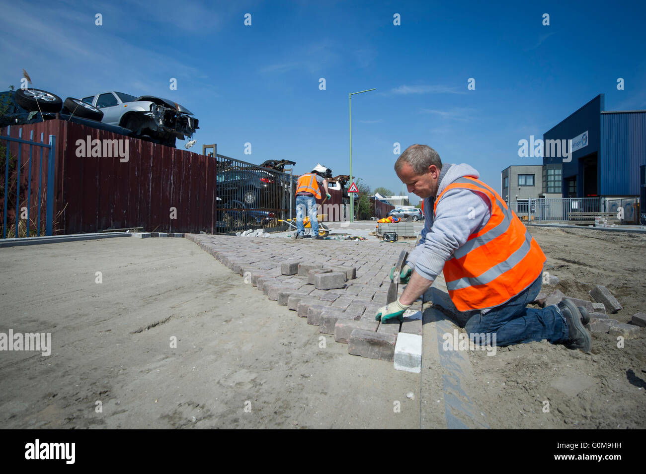 Men laying bricks, working on infrastructure. Stock Photo