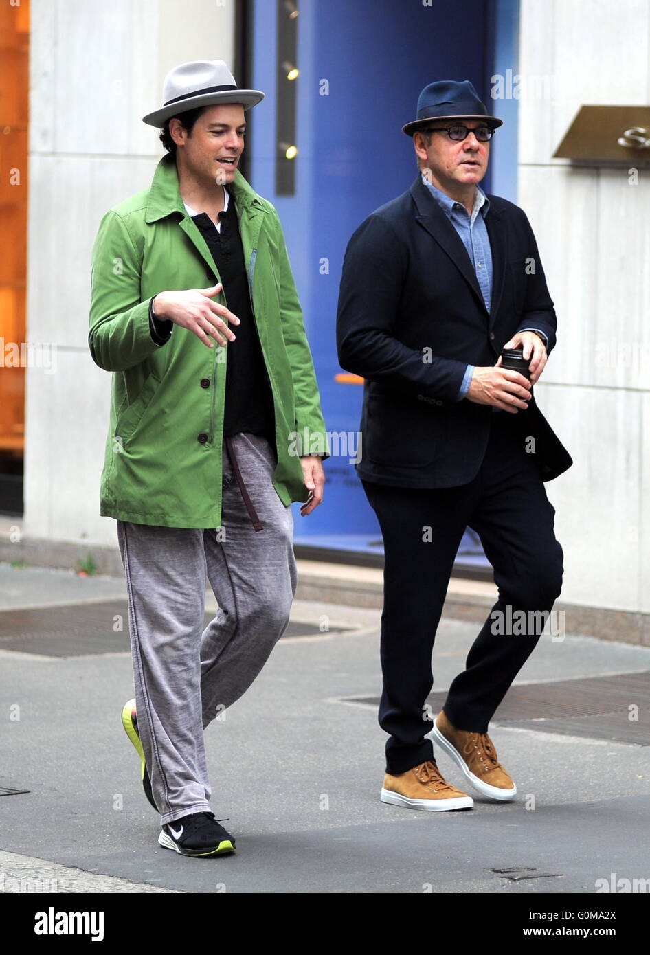 Kevin Spacey takes a stroll with a friend wearing a suit, hat, glasses and carrying a cup coffee from Emporio Armani Caffè. The American Beauty star stops to drink his coffee before entering an Armani store in Milan.  Featuring: Kevin Spacey Where: Milan, Stock Photo