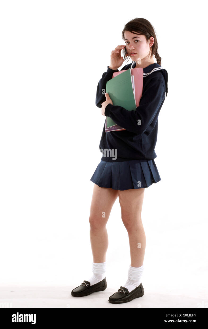 Mixed race young woman dressed in a Japanese style schoolgirls uniform with a very short skirt carrying books Stock Photo