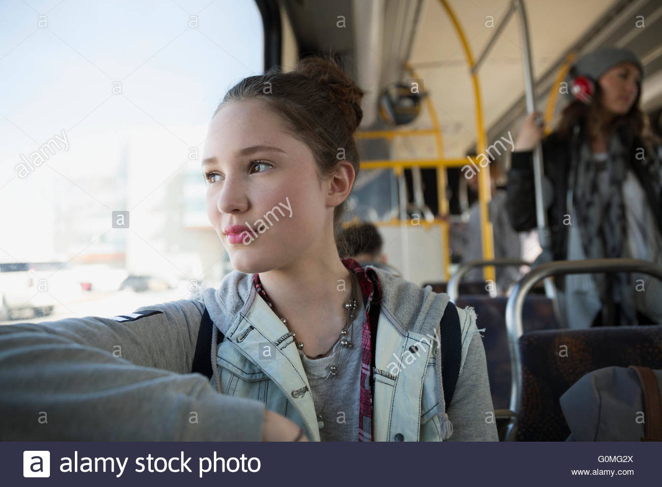 Pensive teenage girl riding bus looking out window Stock Photo