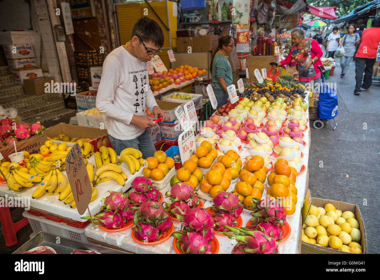 Man and woman selling fresh fruits at the street market in Tai Po, Hong