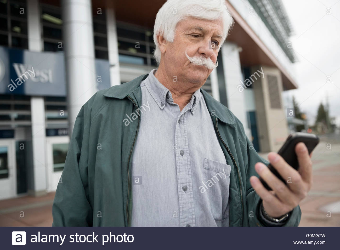 Senior man mustache texting cell phone train station Stock Photo