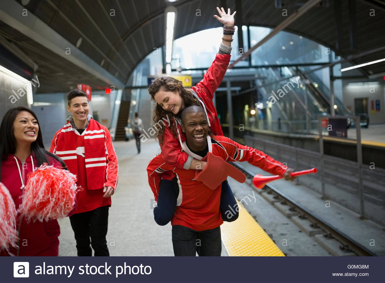 Enthusiastic sports fans red cheering subway station platform Stock Photo