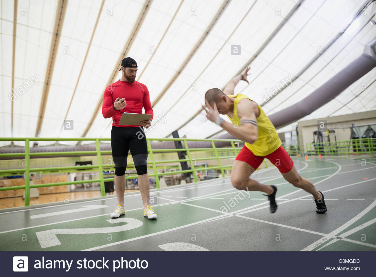 Trainer stopwatch timing runner starting block indoor track Stock Photo