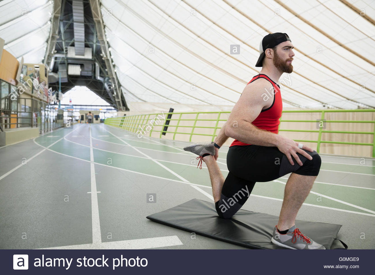 Runner stretching leg kneeling lunge twist indoor track Lunge runner