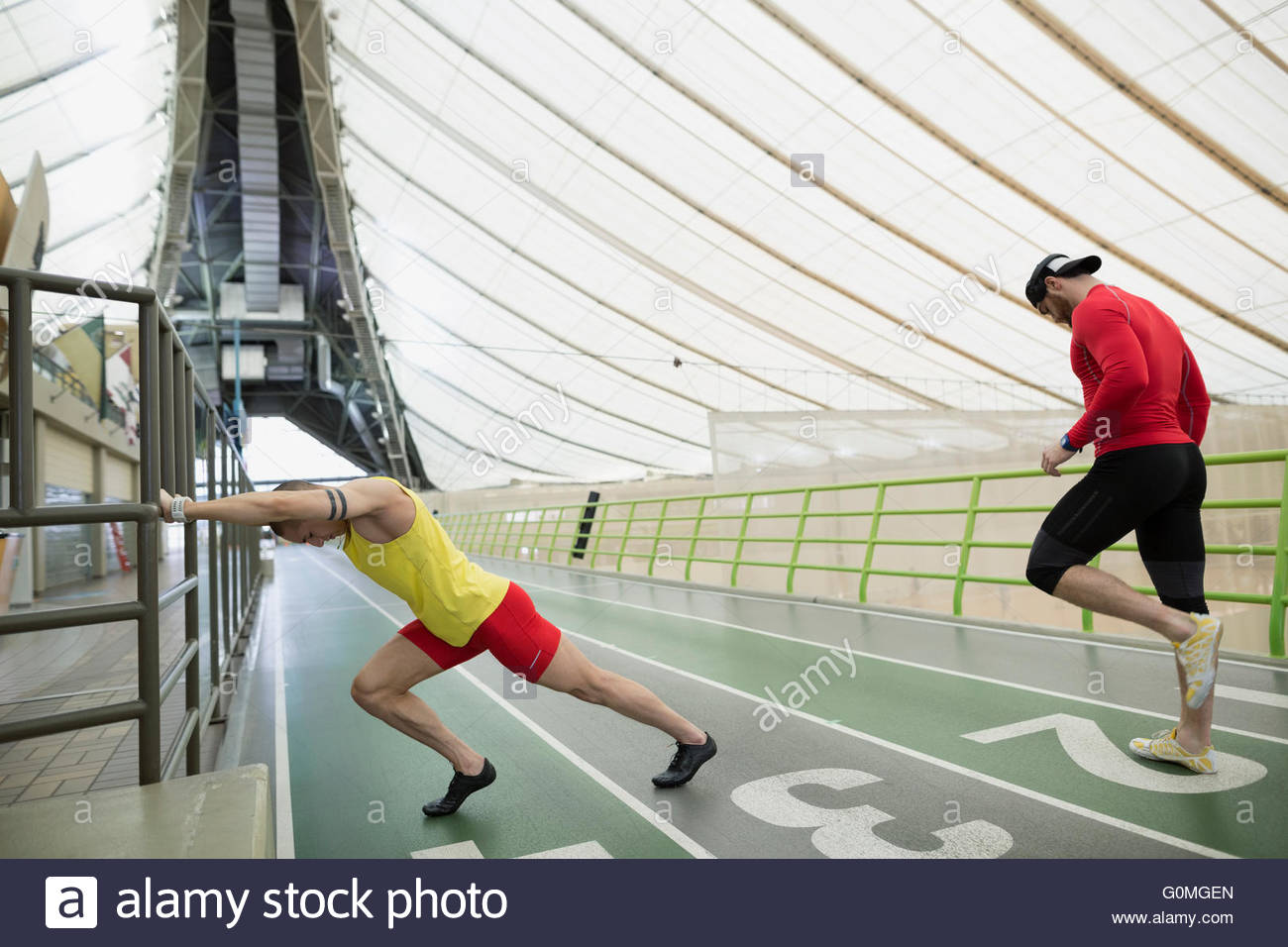 Runners stretching at indoor track Stock Photo Alamy