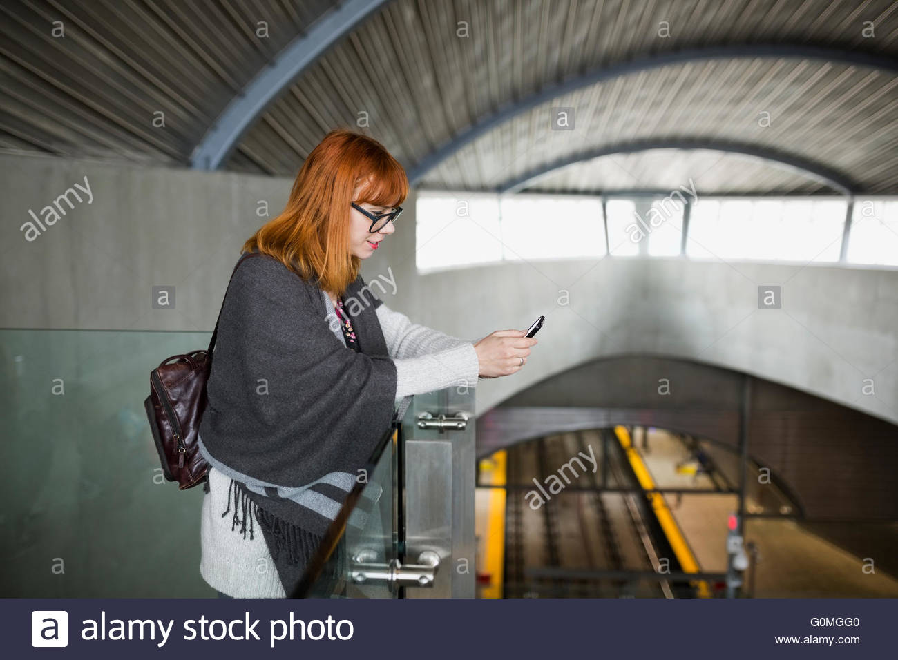 Woman texting with cell phone at train station Stock Photo