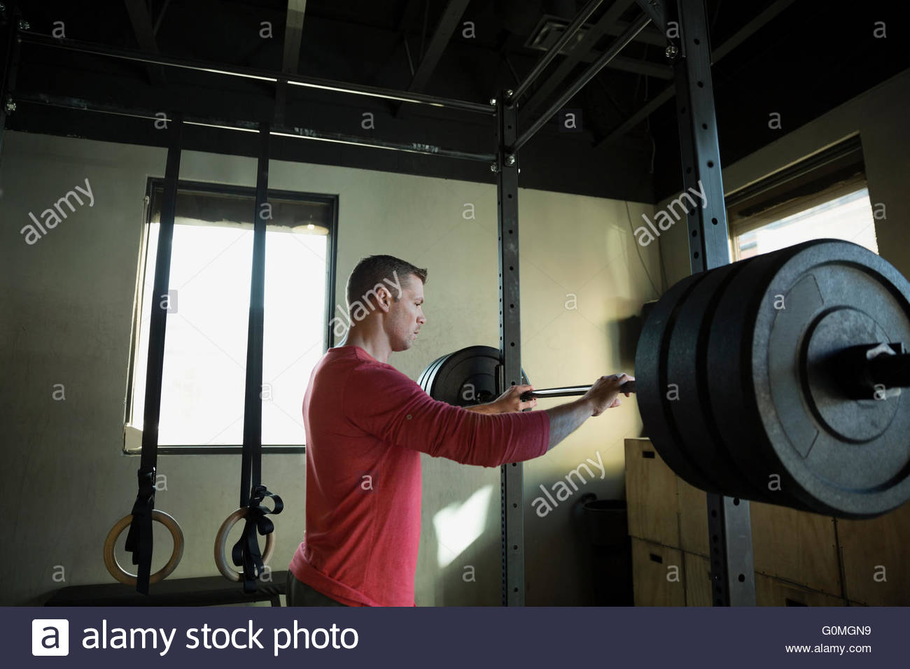 Man standing at squat barbell rack at gym Stock Photo