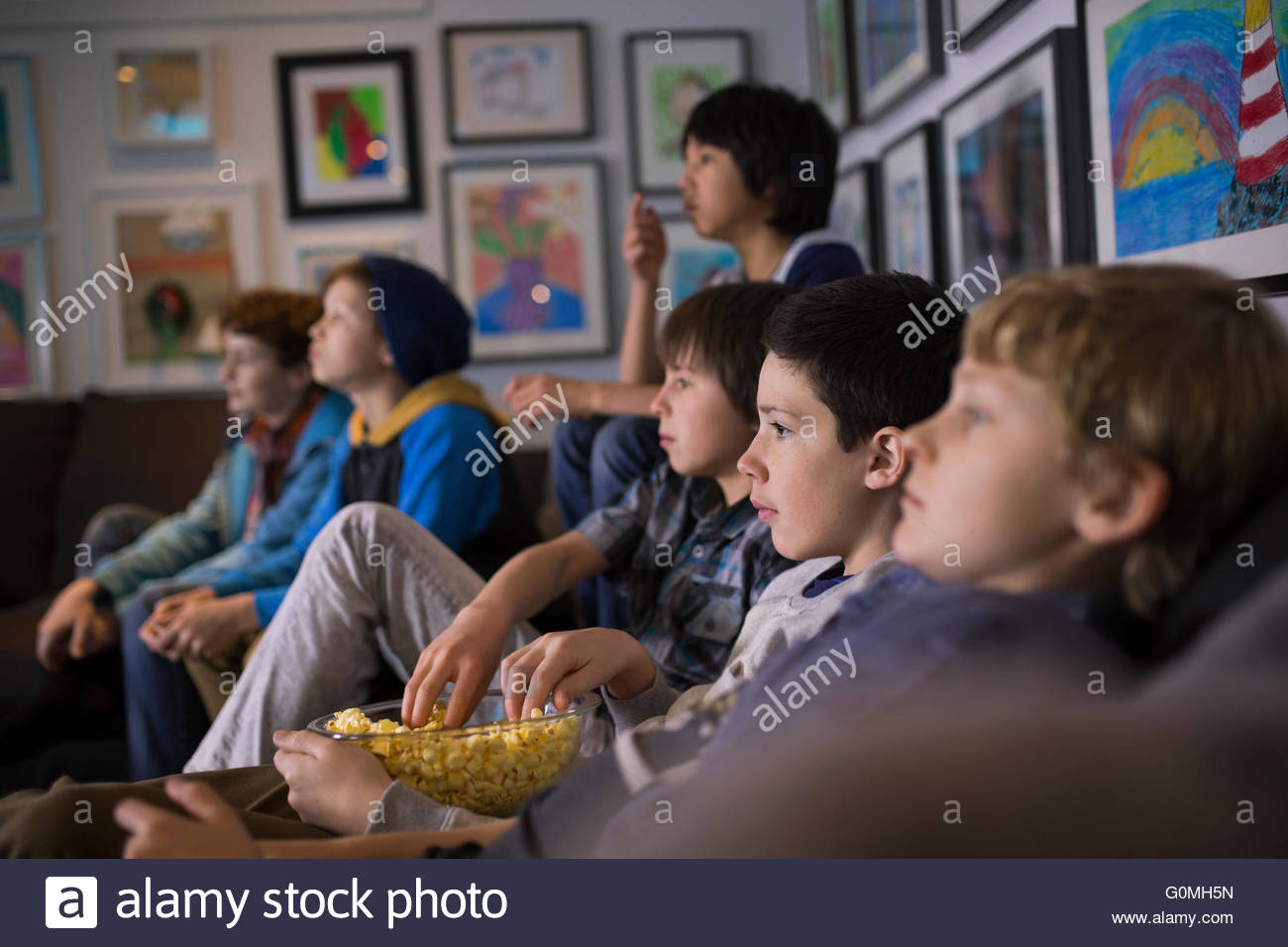 Boys eating popcorn watching TV living room sofa Stock Photo