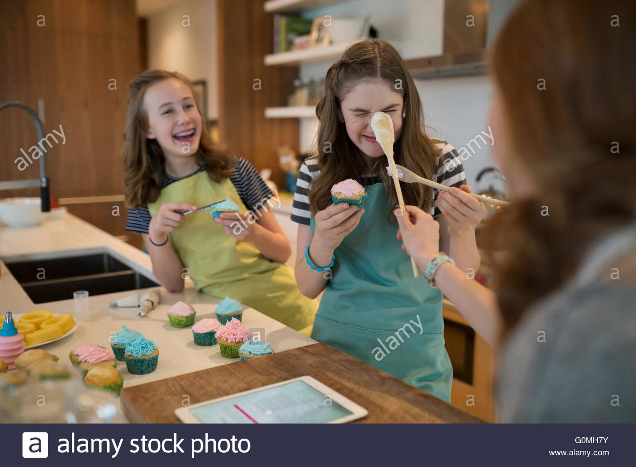 Playful girls frosting cupcakes in kitchen Stock Photo Alamy