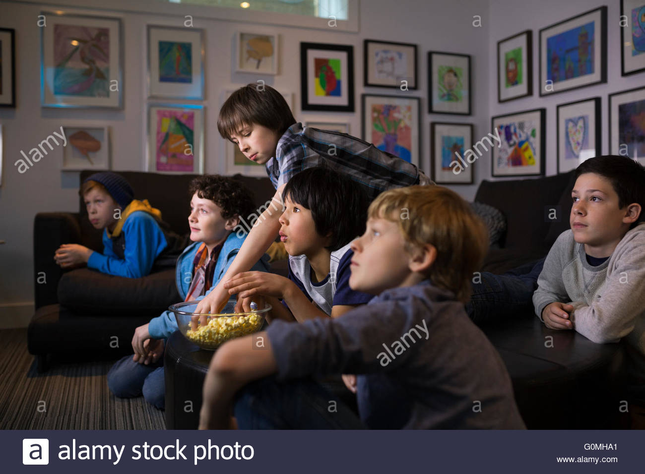 Boys eating popcorn watching TV in living room Stock Photo