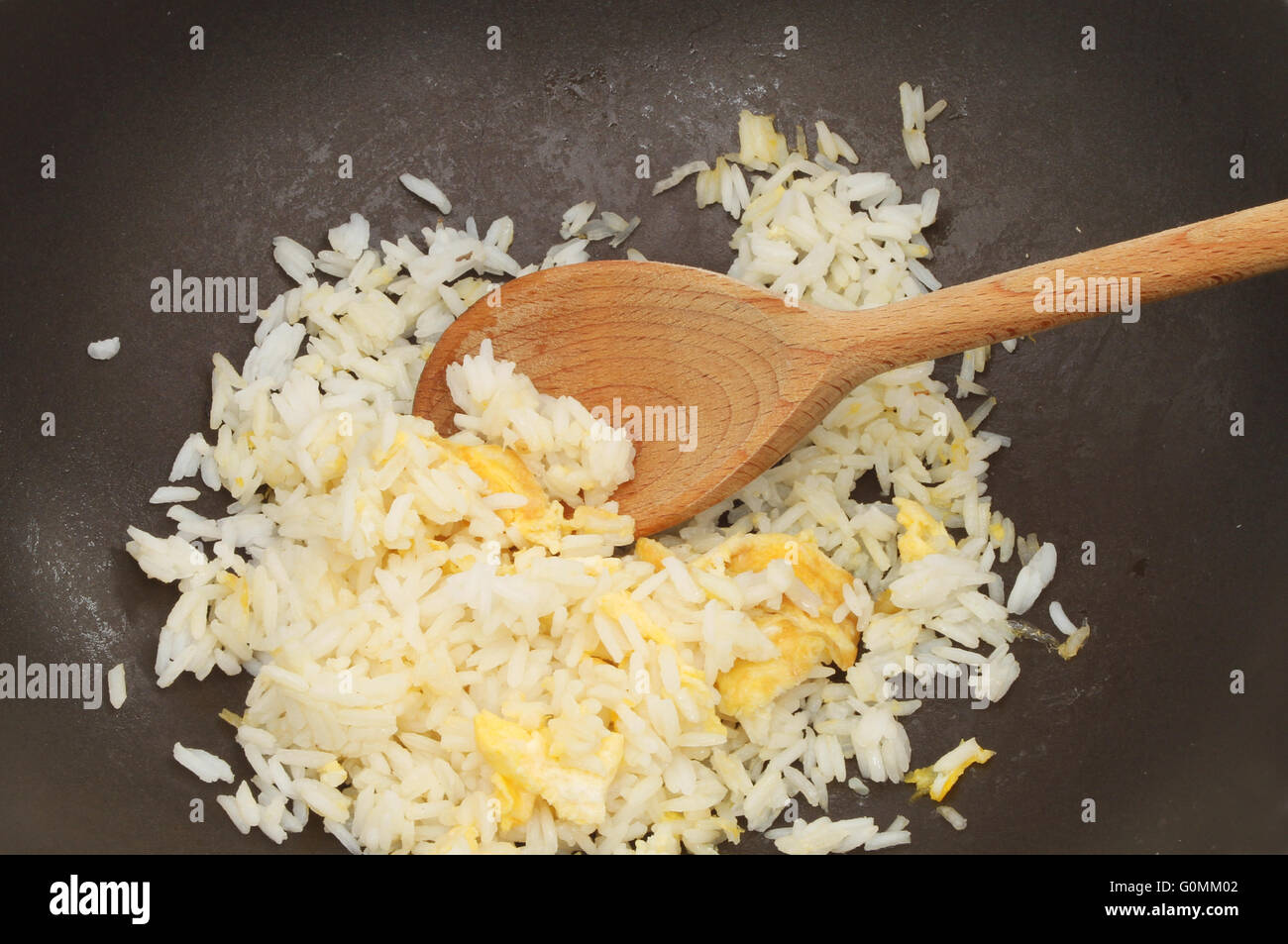 Closeup of egg fried rice in a wok with a wooden spoon Stock Photo