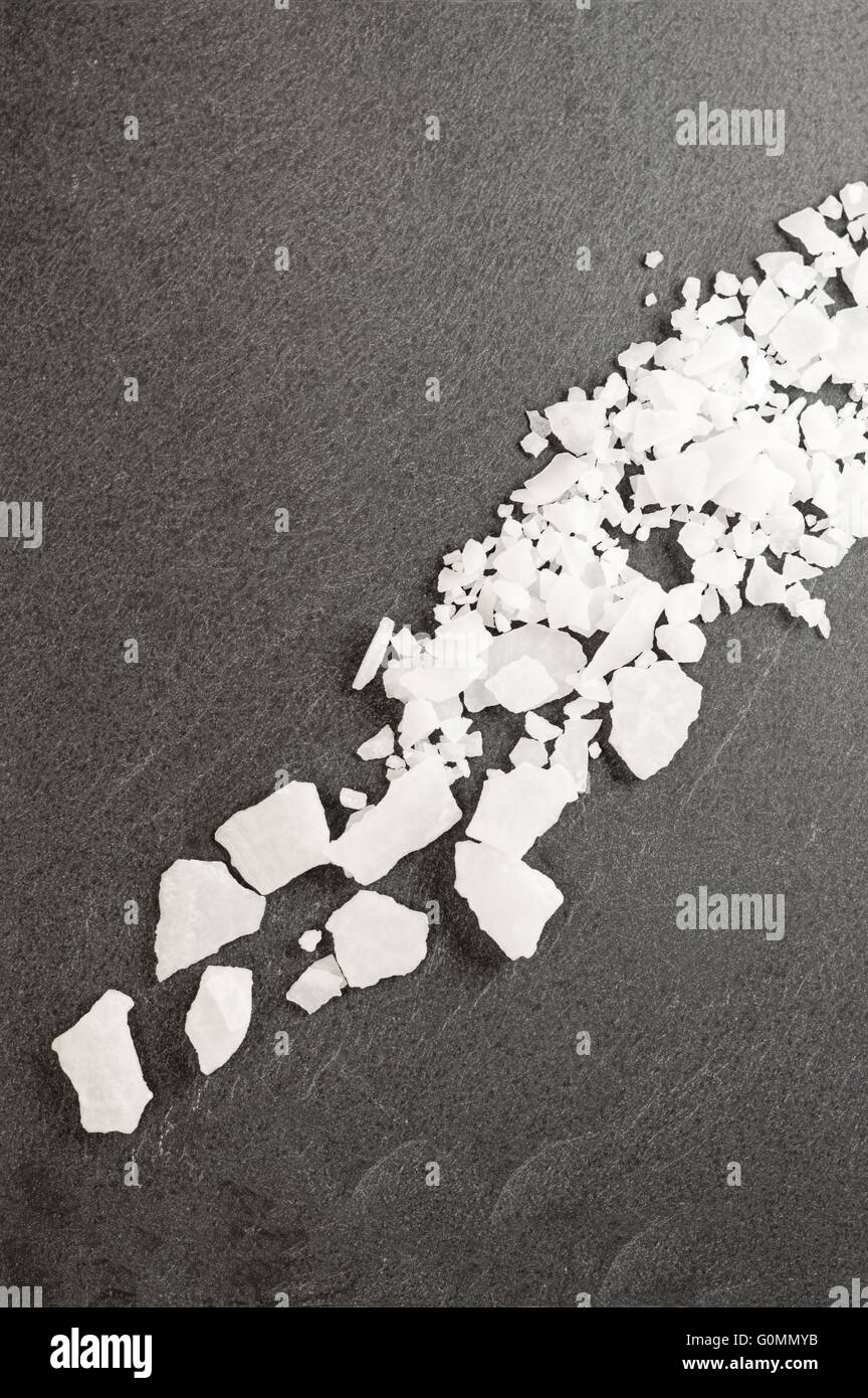 Top view of magnesium chloride flakes on a dark granite slate. Stock Photo