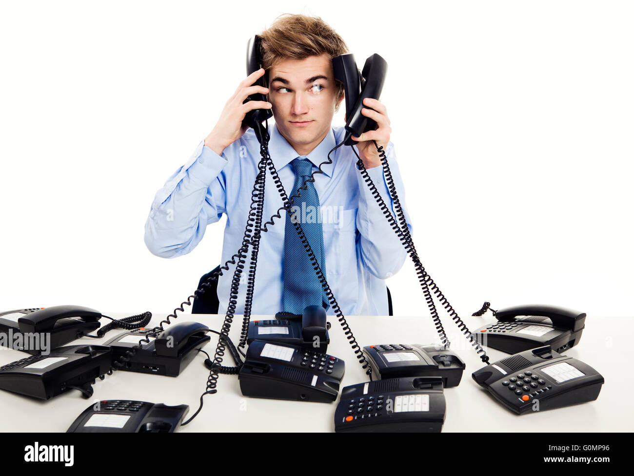 Young man in the office and answering several phones at the same time