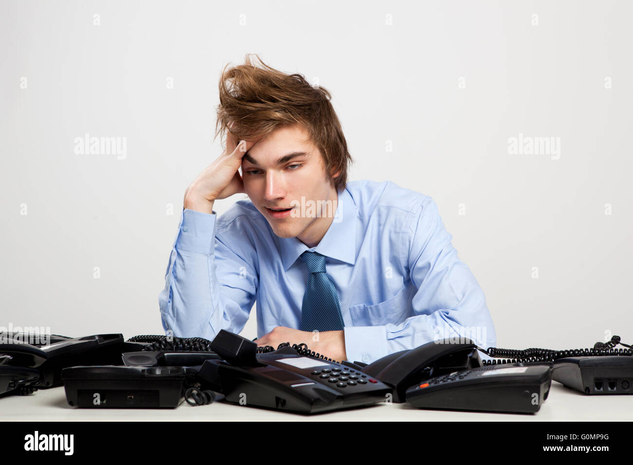 Young man in the office with a bunch of phones on his front Stock Photo ...
