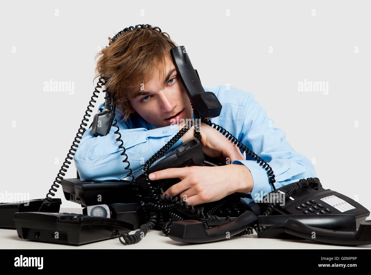 Exhausted man sitting with a bunch of phones over him Stock Photo - Alamy