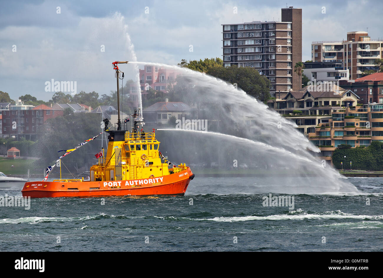 A firefighting tug boat in Sydney Harbour, shooting water into the air Stock Photo