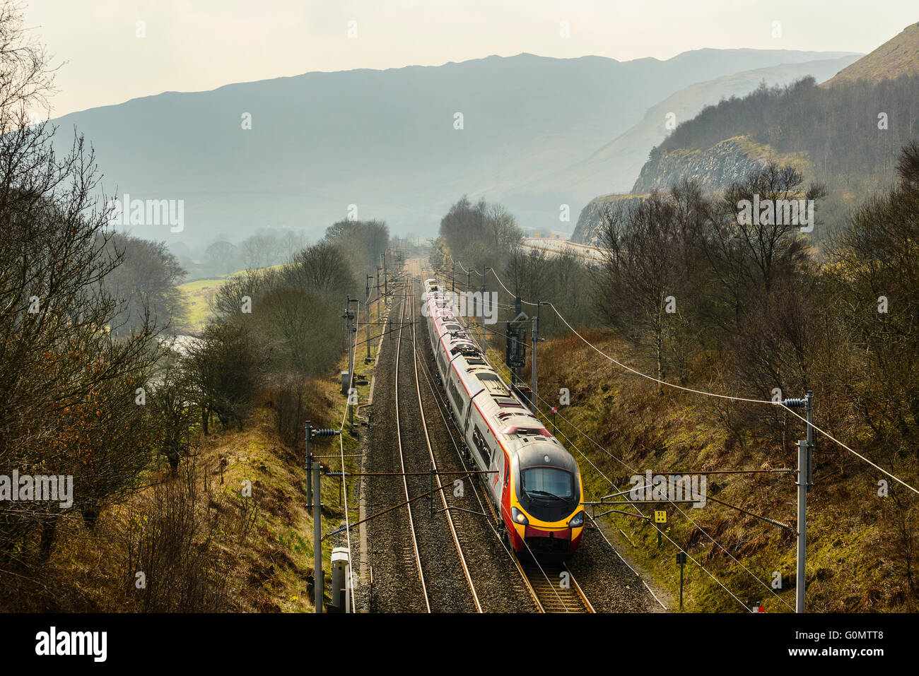 Virgin Pendolino train on West Coast Main Line alongside the M6 motorway in Lune Gorge near Tebay Cumbria Stock Photo