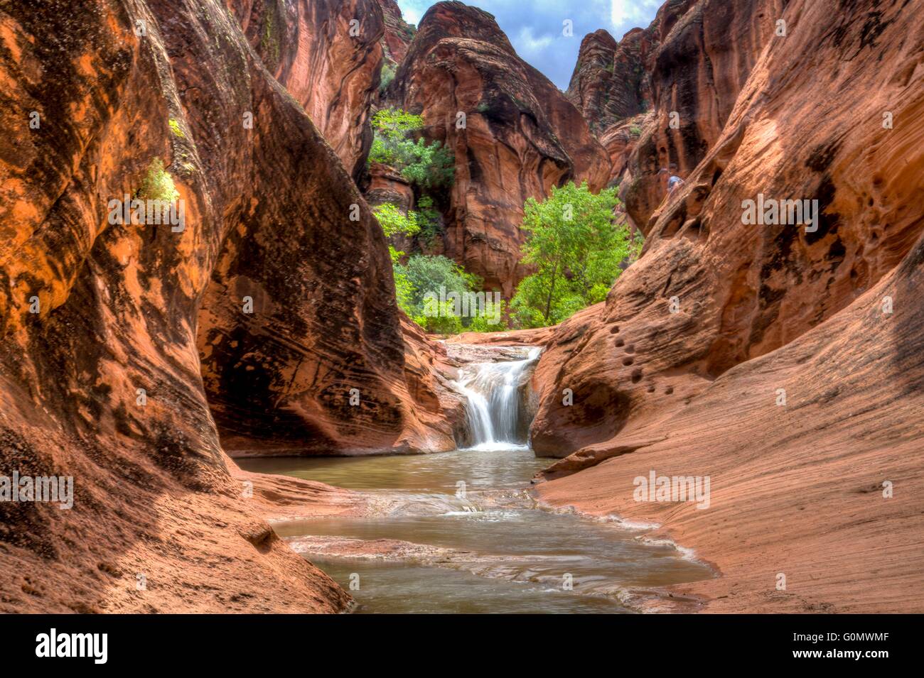 A waterfall spills through the rock hills and desert at the Red Cliffs National Conservation Area where the Colorado Plateau, Great Basin Desert, and Mojave Desert overlap near St. George, Utah. Stock Photo