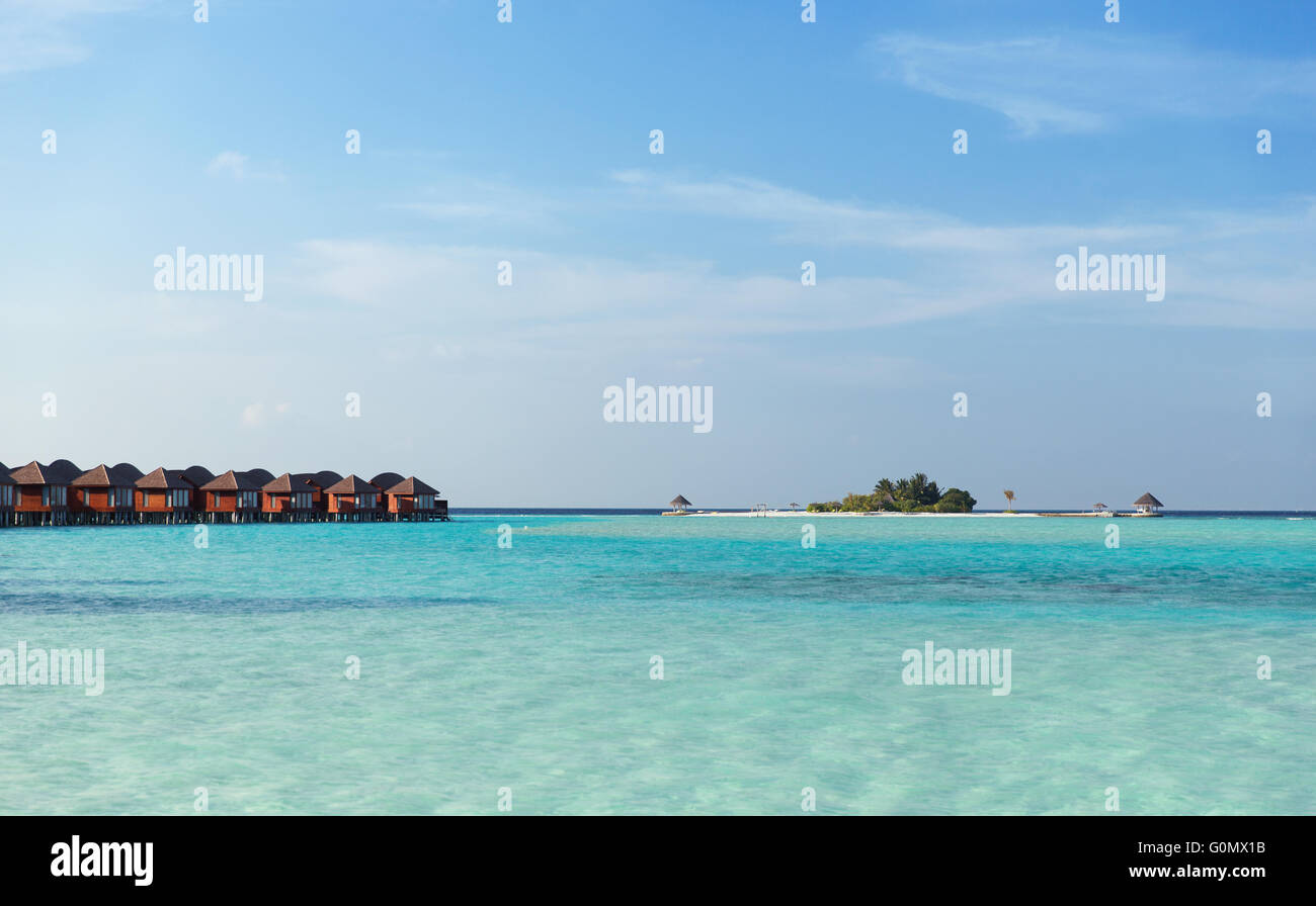 bungalow huts in sea water on exotic resort beach Stock Photo