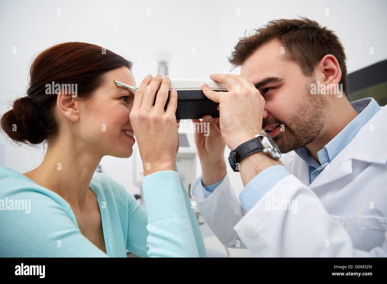 optician with pupilometer and patient at eye clinic Stock Photo