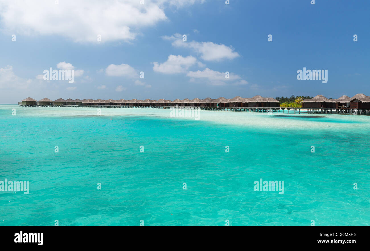 bungalow huts in sea water on exotic resort beach Stock Photo