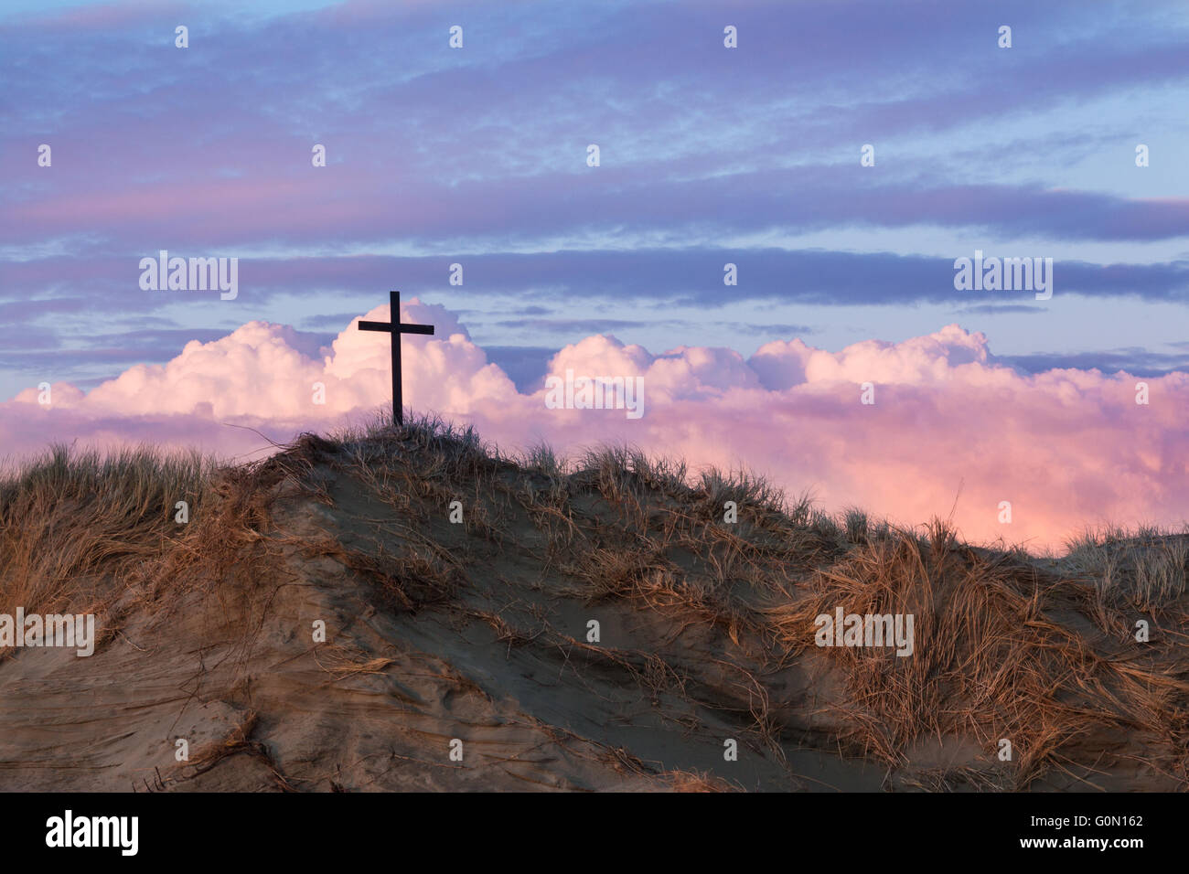 One black cross on a sand dune with some wonderful storm clouds behind ...