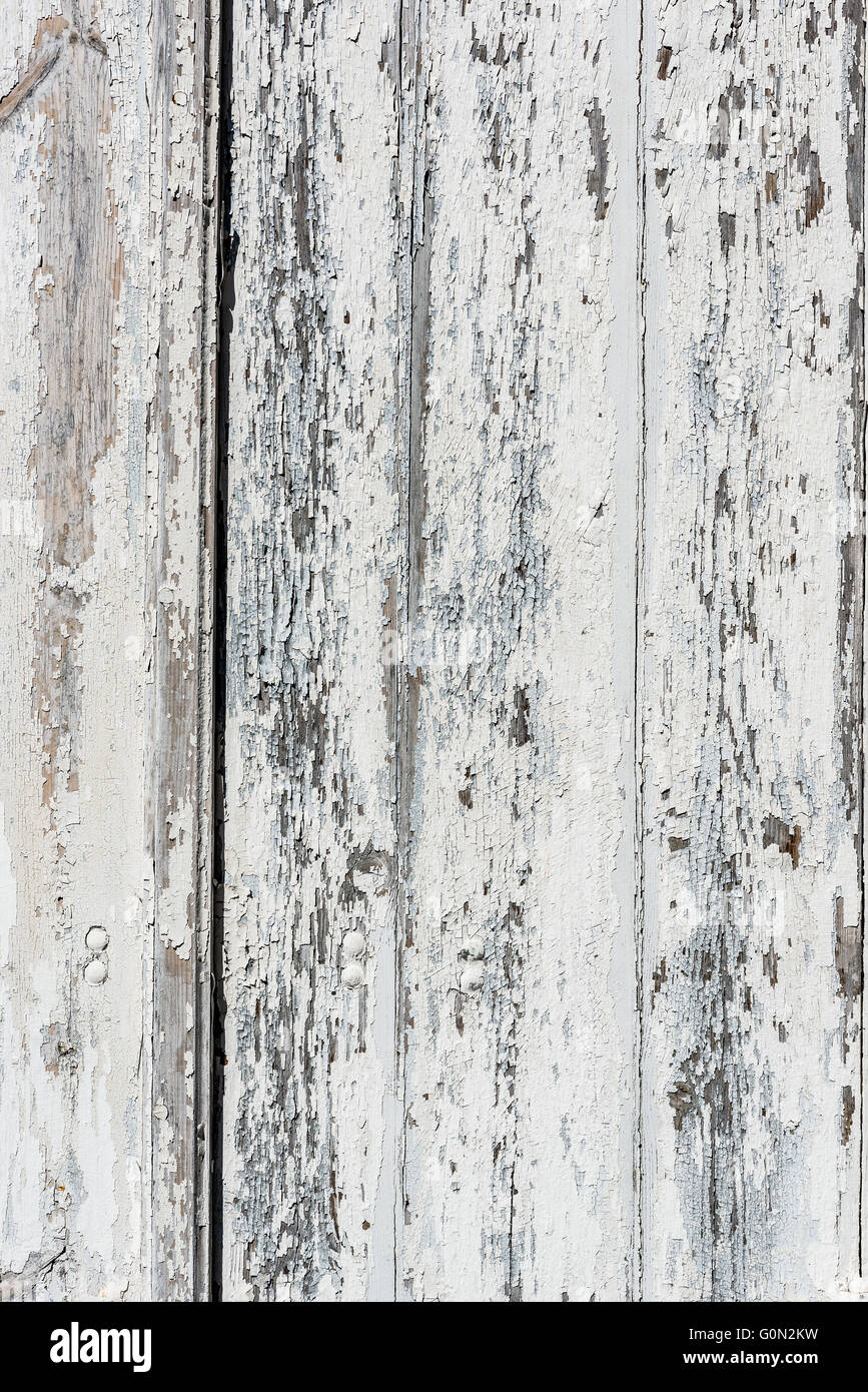 Weathered white wooden background textured with flaking white paint chipped and peeling. Stock Photo
