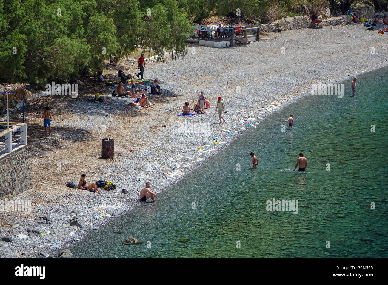 People on beach and in sea with trash garbage rubbish around them Stock Photo