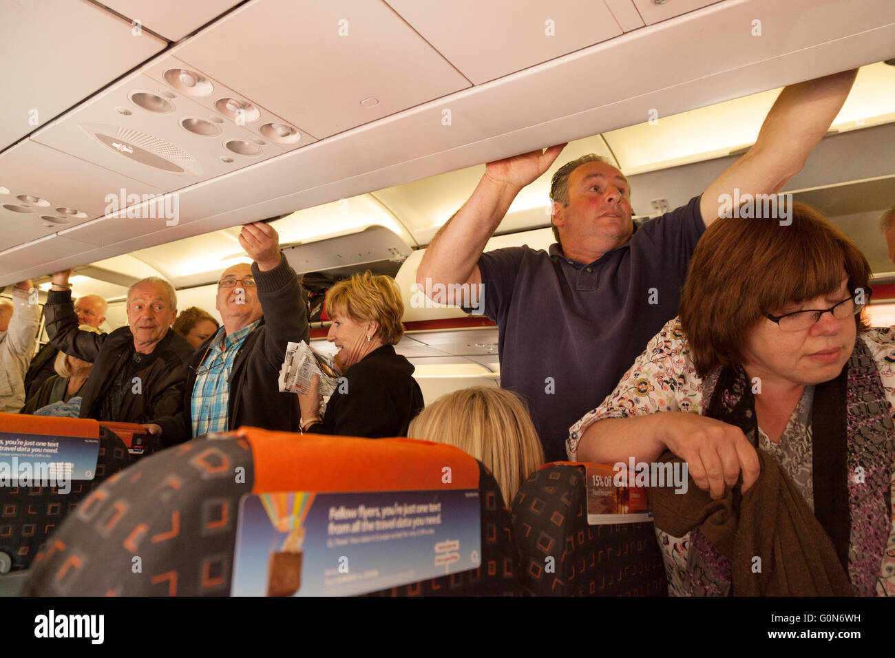 Air passengers getting their hand luggage from the overhead lockers on an Easyjet  flight from Southend airport to Malaga Spain Stock Photo